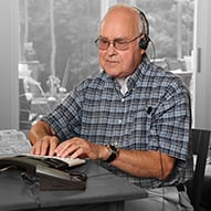 Older adult male wearing a headset and using Hearing Carry-over to make a phone call.